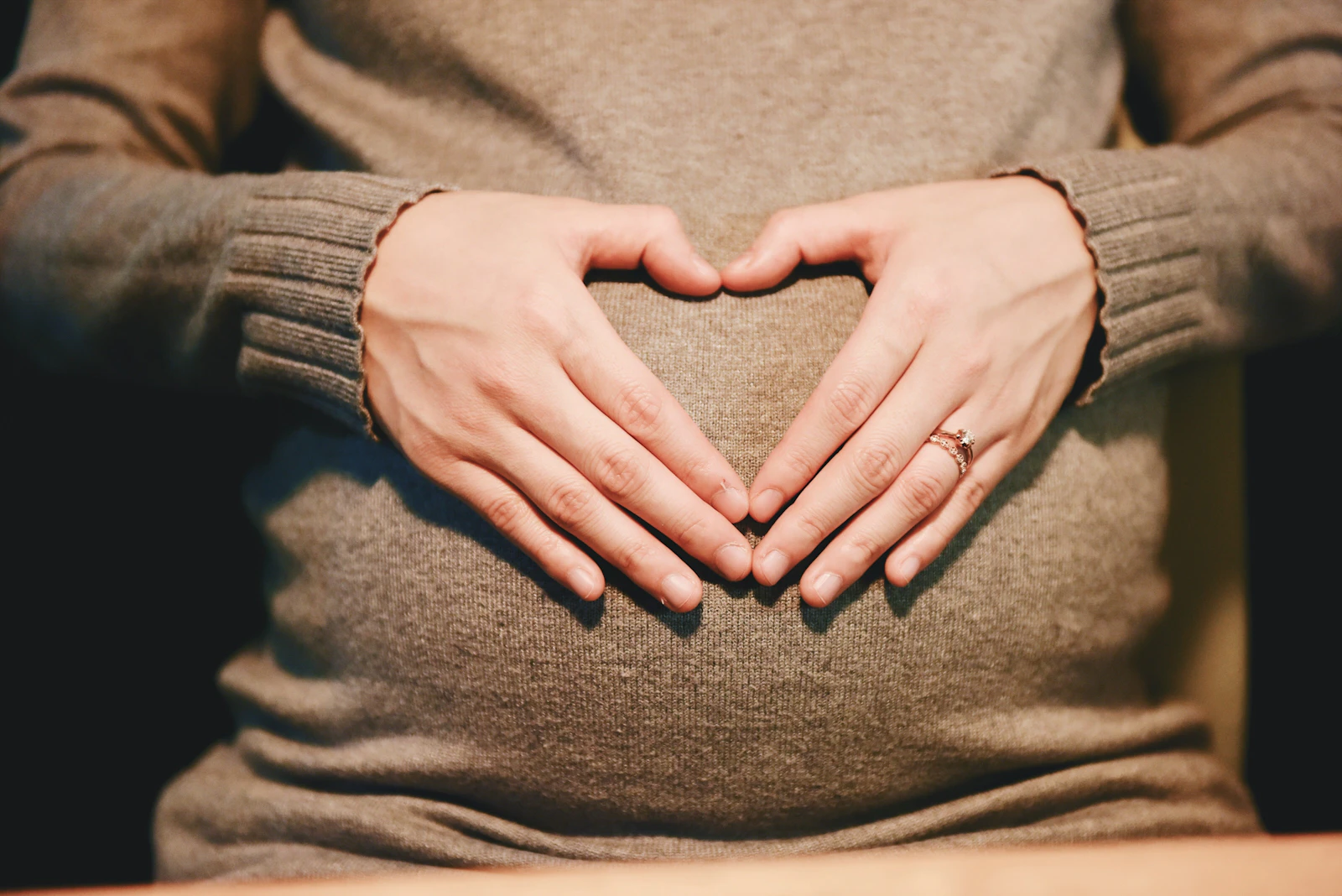 Expectant mother forming a heart with her hands over her belly